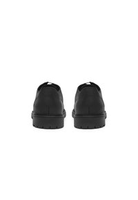 Pantofi din piele neagră cu vârful rotunjit și o talpă joasă din cauciuc texturat. Spatele are o finisare netedă și detalii minime.