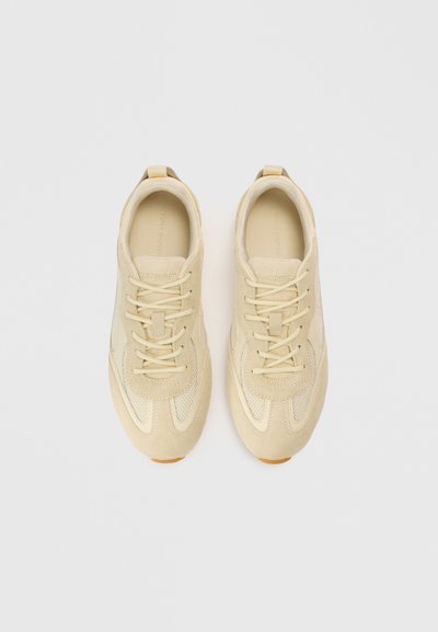 Μπεζ αθλητικά παπούτσια που συνδυάζουν σουέντ και δίχτυ, με επίπεδα κορδόνια, στρογγυλερή μύτη και υφασμένο πάτο.