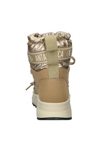 Beige Knöchelstiefel mit schimmerndem, gestepptem Obermaterial, ausgestattet mit einem weißen Logoschlaufen, strukturiertem Absatz und einer robusten weißen Sohle mit schwarzem Boden.