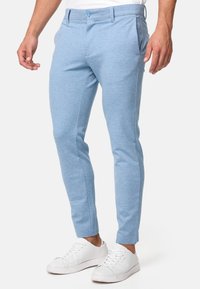 Chino blu chiaro realizzati in un tessuto morbido e testurizzato. Vestibilità su misura con tasche laterali e cuciture frontali. Abbinati a sneakers bianche.