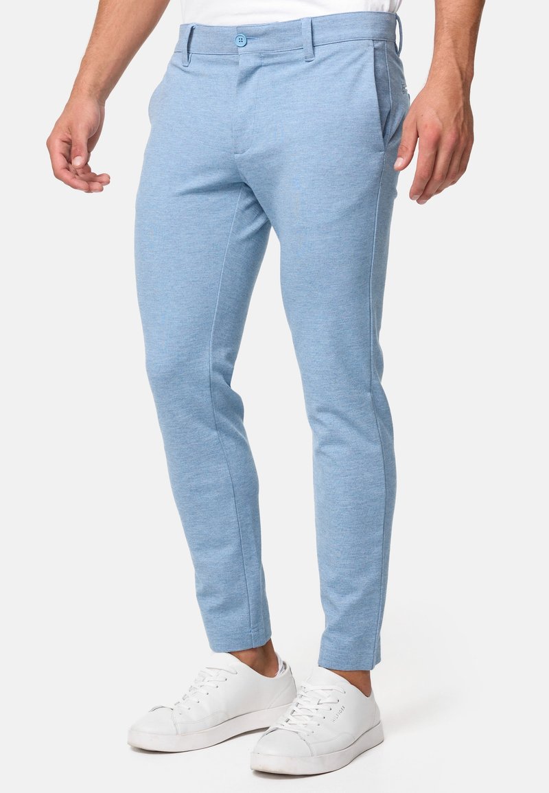Chino blu chiaro realizzati in un tessuto morbido e testurizzato. Vestibilità su misura con tasche laterali e cuciture frontali. Abbinati a sneakers bianche.