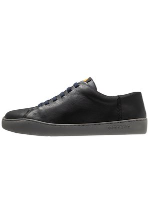 Black leather sneaker with a smooth texture, round toe, navy laces, and a gray rubber sole featuring the brand name "camper."