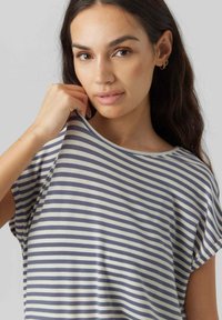 Gestreept T-shirt in crèmekleurig en marineblauw, korte mouwen, brede halslijn, zachte textuur, geposeerd door een persoon die het fabric lichtjes bij de kraag vasthoudt.
