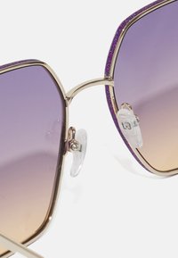 Sunglasses with large, square frames featuring a gradient purple tint, metal hinges, and glittery purple accents along the top edge.