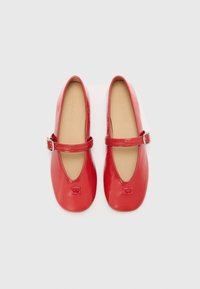 Red patent leather Mary Jane shoes with a rounded toe, a thin ankle strap, and a branded logo embossed at the toe. Smooth texture.