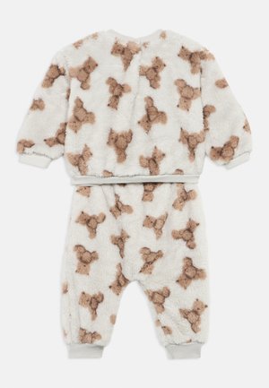 Pyjama doux et blanc pour tout-petit, avec des motifs d'ours en peluche marron, manches longues et poignets élastiques aux manches et aux jambes du pantalon.