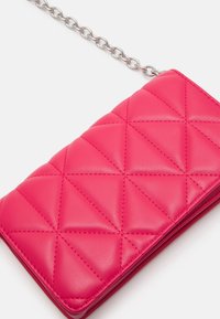 Prošívaná růžová kožená peněženka se stříbrným řetízkovým popruhem, zdobená texturovaným diamantovým vzorem a hladkým povrchem. Kompaktní obdélníkový tvar.
