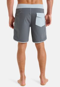 Gray swim shorts with a light gray waistband, featuring a back pocket and contrasting stitching details. Smooth, flexible fabric.