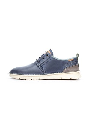 Zapatos de cuero azul marino con una textura suave, que presentan un cuello azul claro, detalles en marrón, cordones y una suela de goma blanca en contraste.