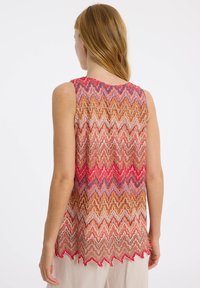 Ärmelloses Oberteil mit mehrfarbigem Zickzackmuster und strukturiertem, welligem Design. Saum mit rohen Kanten in Rottönen, Rosa, Orange und Gold.