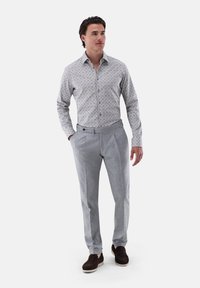 Camicia a maniche lunghe con un motivo grigio chiaro abbinata a pantaloni plissettati grigio chiaro e scarpe marrone scuro. Vestibilità semplice e moderna.