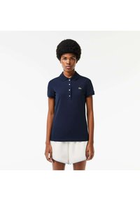 Mörkblå polo-shirt i bomull, med klassisk krage, korta ärmar och en liten grön logotyp på vänster bröst.