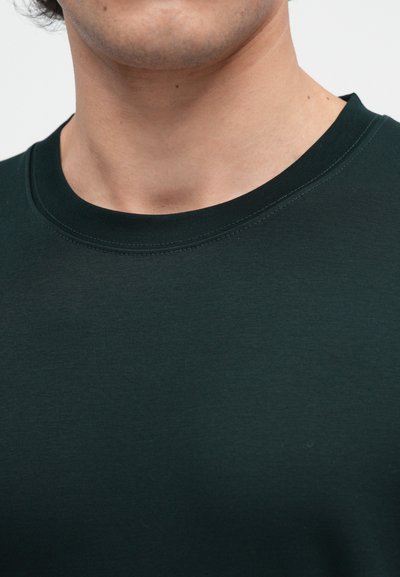 Sötétzöld környakú póló, puha anyagból készült, sima textúrával és diszkrét varrásokkal a dekoltázsnál.