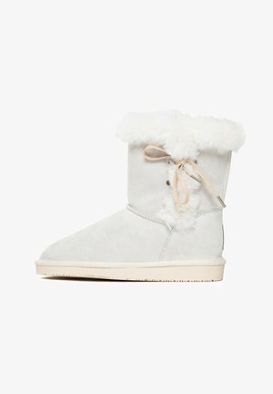 Weiße Wildleder-Stiefelette mit einem Oberteil aus Kunstpelz und Schnürdetails an der Seite. Die Sohle ist beige und verfügt über strukturierten Grip.
