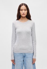 Svetlo šedá dlhá rukávová košeľa vyrobená z mäkkého, elastického materiálu. Má okrúhly výstrih a bočné rozparky na leme pre pohodlie a prispôsobenie.