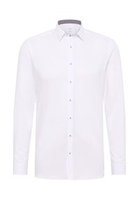 Camicia bianca a maniche lunghe realizzata in tessuto morbido, con una chiusura a bottoni sul davanti e bottoni di tonalità argento, e un dettaglio interno del colletto a fantasia.