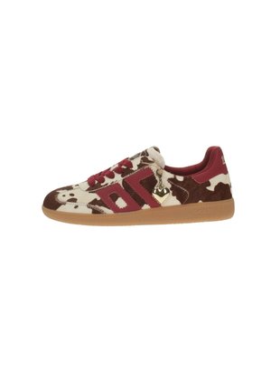 Zapatilla deportiva de perfil bajo con estampado de vaca en marrón y crema, detalles en rojo, cordones rojos, suela de goma y un pequeño colgante en forma de corazón en el lateral.