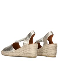 Metallic silver wedge sandals with a woven jute sole, open heel, and front straps. Features a textured upper surface and minimal design.