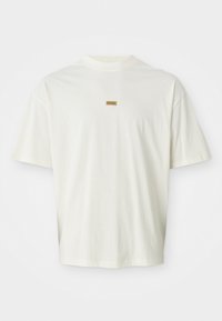 Hvid kortærmet T-shirt lavet af blød bomuld, med et lille brunt "HUGO" mærke centreret på brystet. Løs pasform med rund halsudskæring.