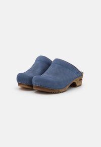 Blauwe leren klompen met een gladde afwerking, gebogen vorm en zigzagstiksels op een houten zool. Textuur onderkant voor grip.