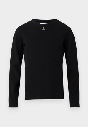 Tricou negru cu mâneci lungi și guler rotund, cu un mic emblemă multicoloră centrată aproape de guler, pe un fundal deschis simplu.