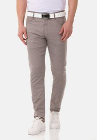 Herren Slim-Fit gestreifte Hose aus hellgrauem Stoff, mit einem weißen Gürtel, kombiniert mit weißen Sneakers. Vertikale Streifen betonen das Design.