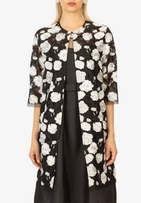Schwarze Spitzenjacke mit weißer Blumenstickerei, offenes Design an der Vorderseite, Dreiviertelärmel und hoher Halsausschnitt. Glatte Innenauskleidung und keine Verschlüsse.
