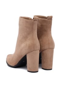 Pieskové semišové členkové topánky s hladkou textúrou, štvorcovou špičkou a robustným vysokým podpätkom. Obsahujú zadný zips pre jednoduchý prístup.