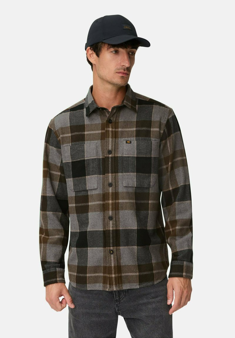 Geruite shirt in grijs, zwart en bruin tinten met twee borstzakken. De stof lijkt zacht, met een knoopsluiting en een klassieke kraag. Draag het met een donkere pet.
