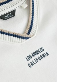 Witte sweatshirt met een marineblauwe en beige geribbelde kraag. Voorzien van geborduurde "LOS ANGELES CALIFORNIA" in donkerblauw op de voorkant.