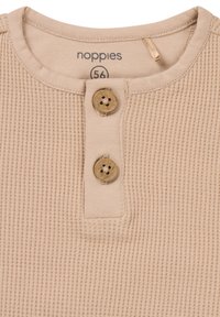 Beige geripptes Henley-Shirt mit einer Knopfleiste mit zwei Holzknöpfen, Rundhalsausschnitt und weichem Baumwollstoff. Größenetikett: 56.