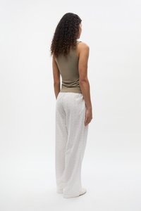 Olive tank top with slim fit, paired with white wide-leg pants featuring a textured pattern and elastic waistband.