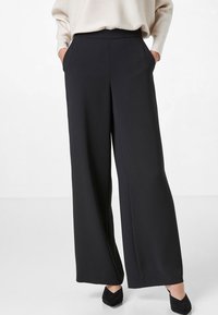 Wijdvallende zwarte broek van een gladde stof, hoge taille, zijzakken en een glanzende afwerking. Geschikt voor verschillende gelegenheden.