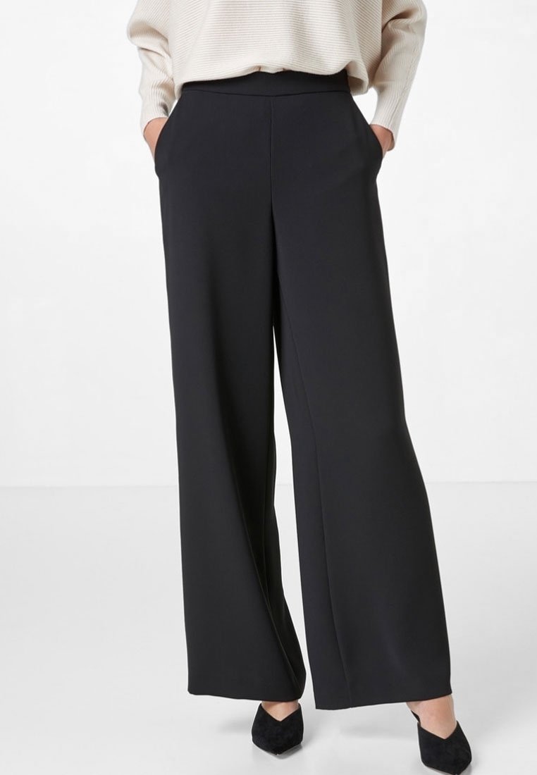Wijdvallende zwarte broek van een gladde stof, hoge taille, zijzakken en een glanzende afwerking. Geschikt voor verschillende gelegenheden.