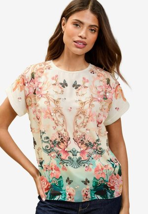 Bluse mit Blumenmuster in einer Kombination aus rosa und türkis, aus transparenter Stoffqualität, mit kurzen Ärmeln und dekorativen Verzierungen, einschließlich Schmetterlingen.