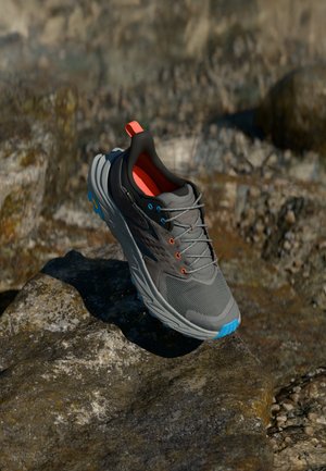 Gray athletic shoe with a mesh upper, orange and blue accents, and a textured sole. Features a cushioned collar and reflective details.