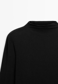 Schwarzer Rollkragenpullover mit gerippter Struktur, hohem Kragen und eng anliegenden langen Ärmeln, mit einem glatten, weichen Stofffinish.