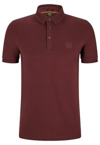 Burgundy pikétröja med krage, treknappsstängning och korta ärmar. Har en subtil logotypapplikation på bröstet och ett mjukt, strukturerat tyg.