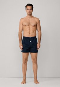 Tmavě modré vzorované boxerky vyrobené z měkké látky, s pasem se zapínáním na předním knoflíku a svislými pruhy v zelené a červené barvě.