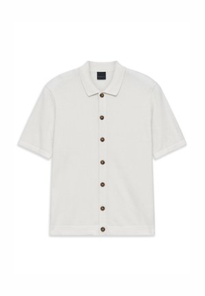 Weißes kurzärmliges Strickshirt mit Kragen und sieben braunen Knöpfen vorne, flach auf einem weißen Hintergrund ausgelegt.