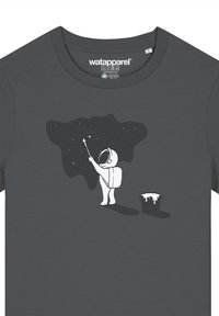 Donkergrijze t-shirt met een witte illustratie van een astronaut die naar sterren reikt, met een verfemmer naast hem. Glad stoffen textuur.
