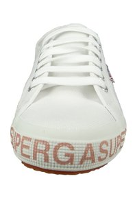 White canvas sneaker with round toe, lace-up front, textured upper, and rubber sole. Features "SUPERGA" printed in pink on the side.