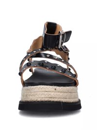 Sandal in pelle nera con cinturini e dettagli borchiati, suola in juta stile espadrilles e cinturino alla caviglia con fibbia. Suola piatta nera e dettagli testurizzati visibili.