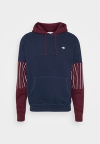 Mörkblå hoodie med vinröda ärmar. Har en framficka, justerbar dragsnöre och ett vitt randmönster på vänster ärm.