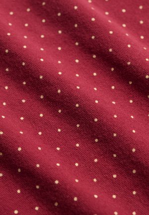 Tela roja con pequeños lunares blancos uniformemente espaciados, mostrada en primer plano, destacando la textura y el patrón.