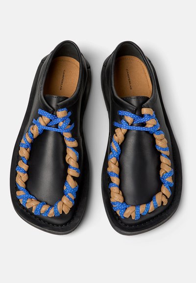 Chaussures en cuir noir à enfiler avec un détail tressé couleur tan enveloppé de cordons bleus, dotées d'orteils carrés arrondis et de semelles intérieures rembourrées.