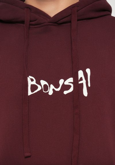 Bordová mikina s textúrovaným povrchom, s bielym ručne kresleným logom "BONS41" na prednej strane a nastaviteľnými šnúrkami na kapucni.