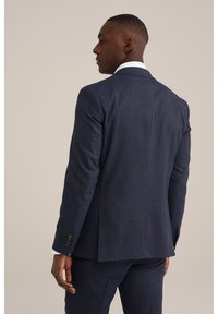 Veste de costume texturée bleu marine avec une coupe ajustée, fente simple au dos et détails de poignet à trois boutons. Design épuré et moderne.
