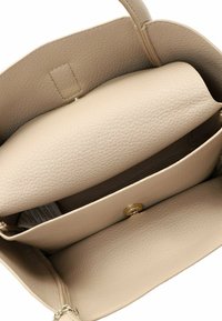 Beige leren handtas met een geprofileerde textuur, voorzien van twee hoofdcompartimenten en een gouden drukknoopsluiting. Kettinghengsel zichtbaar.