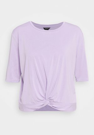 Fioletowa koszulka z krótkim rękawem, okrągłym dekoltem i węzłem na przodzie u dołu, prezentowana na jednolitym tle.